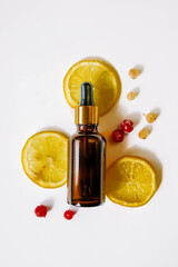 Bottle of essential oil with lemons and berries on white background 