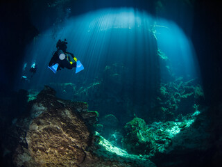 Scuba diving under sunbeams into a cenote (Cenote Ponderosa, Playa del Carmen, Quintana Roo, Mexico)