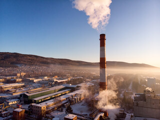 Air pollution by smoke coming out of two factory chimneys. Industrial zone in the city.