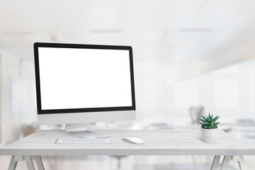 Computer display mockup on office desk. Free space beside for promo text. Clean desk with plant, keyboard and mouse