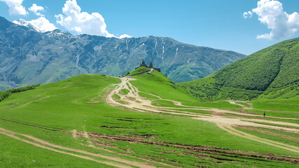 Fototapeta na wymiar Panoramic view of the Caucasus Mountains and the Trinity Church in Gergeti. Georgia