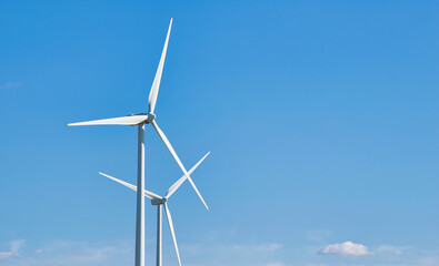 Un par de molinos de viento produciendo energía eólica verde