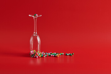 inverted glass goblet with scattered sweets on a red background