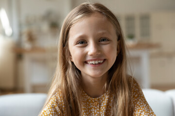 Close up headshot portrait of smiling little 8s Caucasian girl child look at camera talk on video...