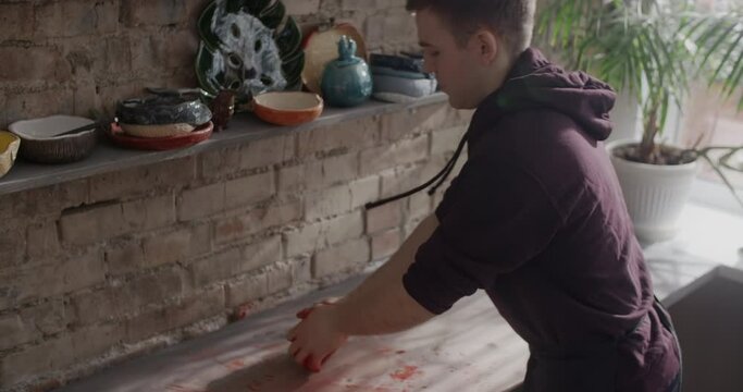 Potter kneads clay with dye in slow motion, pottery at workshop, potter prepares clay for making nerikomi style ceramics, ceramist at work, 4k 60p Prores HQ 10 bit