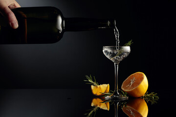 Gin with lemon and rosemary on a black reflective background.