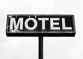 Black and white photo of Large dilapidated and peeling motel sign in the South