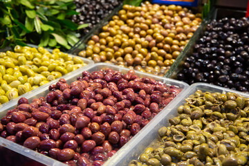 Close up of various olives standing in plastic container on deli counter in market place