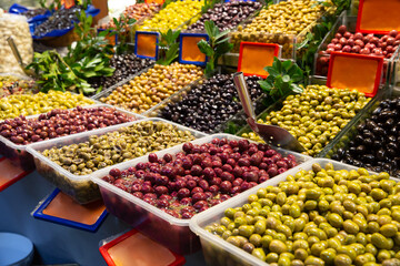 Fototapeta na wymiar Close up of various olives standing in plastic container on deli counter in market place