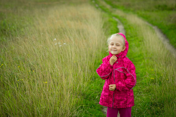blonde girl in pink jacket outdoors. selective focus