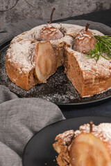 Delicious spice cake with pear, ginger and cinnamon on a dark kitchen counter.