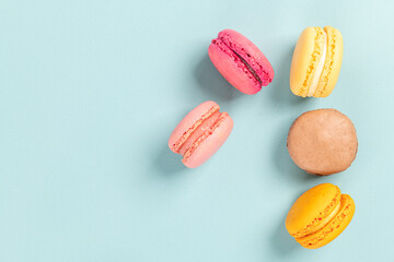 Cake macaron or macaroon on turquoise background from above, colorful almond cookies, pastel colors, vintage card, top view