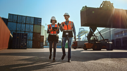 Multiethnic Female Industrial Engineer with Tablet Computer and Male Foreman Worker in Hard Hats...