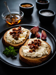 Breakfast - cottage cheese, bread, bruschetta and  vegetables on black wooden table
