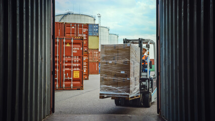 Forklift Driver Loading or Unloading a Shipping Cargo Container with a Full Pallet with Carboard...