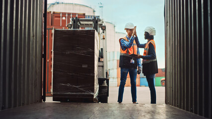 Forklift Driver Loading a Shipping Cargo Container with a Full Pallet with Boxes in Logistics Port...