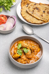 spicy gravy chicken served in a  bowl with butter naan