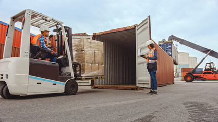 Forklift Driver Loading a Shipping Cargo Container with a Full Pallet with Boxes in Logistics Port...