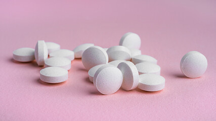 White tablets on a pink background.