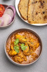spicy gravy chicken served in a  bowl with butter naan