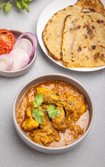 spicy gravy chicken served in a  bowl with butter naan