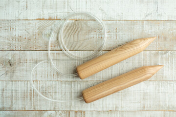 Thick wooden knitting needles for knitting large items with merino wool on a wooden floor