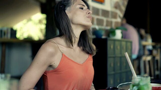 Young woman gets stomach ache during breakfast in cafe, 4K

