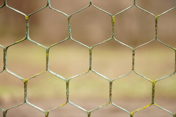 old rusty hexagonal mesh fence closeup with blurred bokeh.