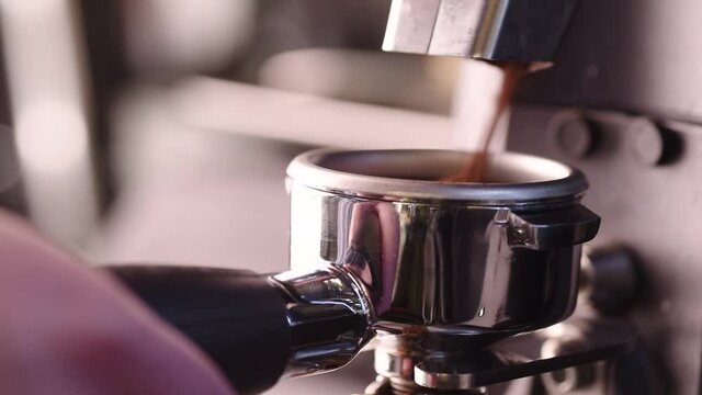 Close shot of Electric Grinder Grinds Coffee Beans In steel chiny filter Holder.