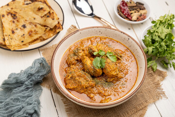 spicy gravy chicken served in a  bowl with butter naan