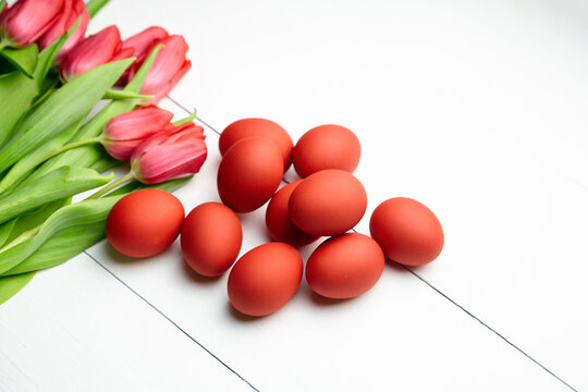 Easter Eggs And Red Flowers On White Wooden Table