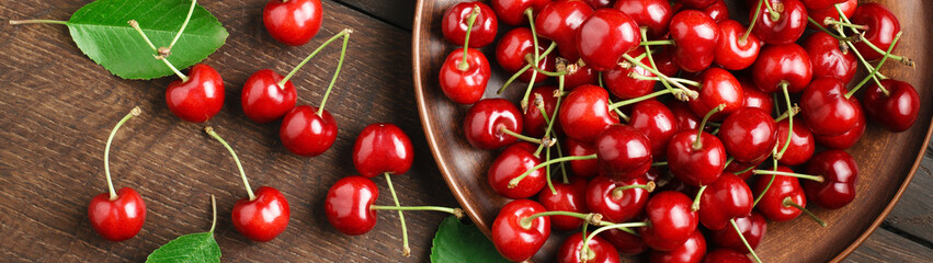 Ripe cherries berries on a wooden table and in a bowl top view banner