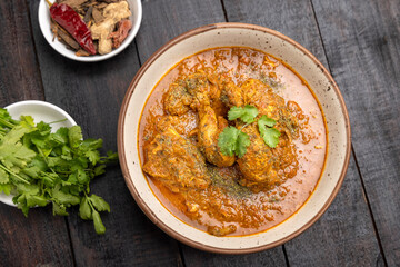 spicy gravy chicken served in a  bowl with butter naan