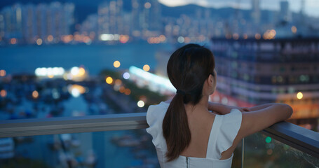 Woman look at the city view at night from balcony