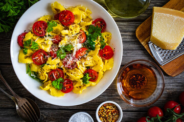 Tortellini stuffed with prosciutto ham and vegetables on wooden table

