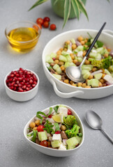 fresh green salad served in a white bowl with beans, legumes, and pomegranate seeds