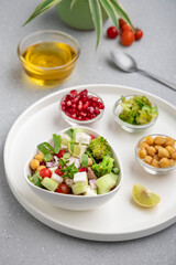 fresh green salad served in a white bowl with beans, legumes, and pomegranate seeds