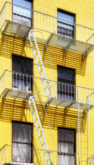 Fototapeta na wymiar Old yellow building with iron fire escape, New York City, USA.