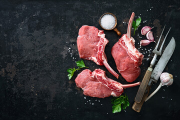 Raw veal Frenched Racks meat with ingredients on rustic dark background