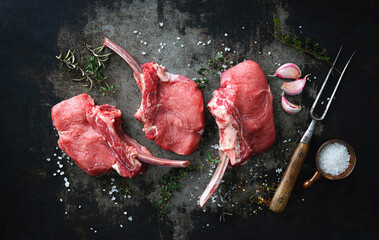 Raw veal Frenched Racks meat with ingredients on rustic dark background