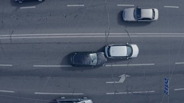 Two cars accident - top view drone shot of two crushed cars on the road. Cars go around the scene of an accident.