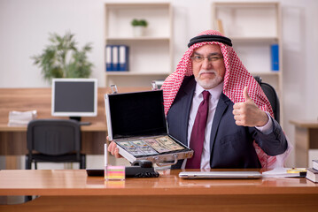 Aged arab businessman employee holding case with banknotes in th