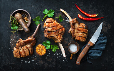 Grilled veal meat ribs cutlets with ingredients on rustic dark background