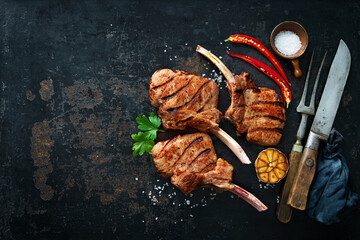Grilled veal meat ribs cutlets with ingredients on rustic dark background - obrazy, fototapety, plakaty