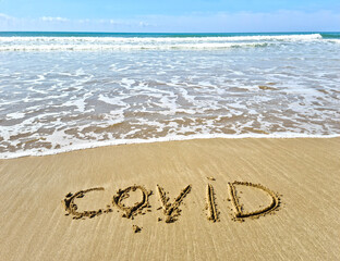 The sea wave washes away the inscription covid.