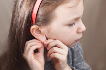 A girl preschooler puts an earring in the ear wrong.