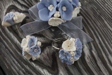 Handmade jewelry. Earrings, brooch and ring made of polymer clay. They lie on pine boards.