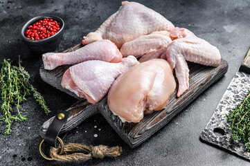Raw chicken portions for cooking and barbecuing with skinless breasts, drumstick and wings. Black...