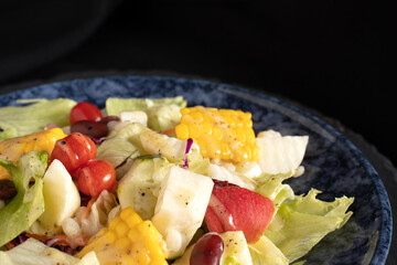 Fresh vegetable salad and fruit salad on black background