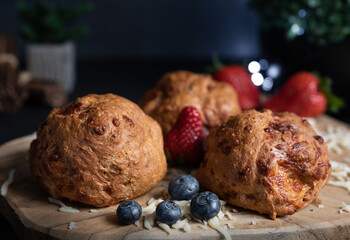 Breakfast, fruit, strawberries, blueberries, crunchy crust of home baked flax flour bagels with mozzarella cheese, wooden board, selective focus, dark background. Natural light, fairy lights. 